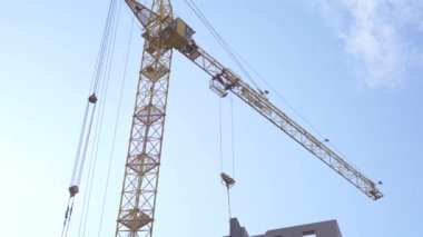 Vinçle inşa edilmiş modern bir bina. Gökyüzünün altında yüksek vinçle inşa edilen binanın altından.