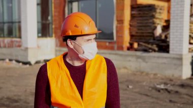 İnşaat miğferinde mühendis ve inşaat alanında antiviral koruyucu maske.  