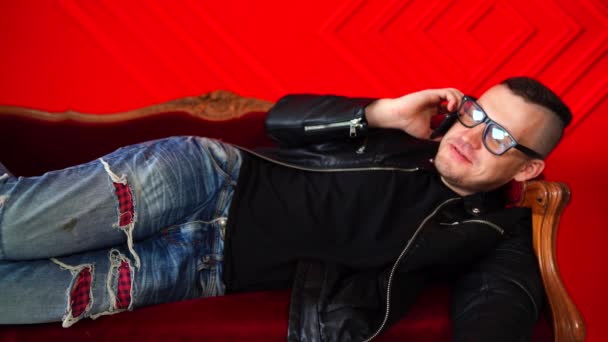 Schöner Junger Mann Mit Brille Auf Kleinem Sofa Vor Roter — Stockvideo