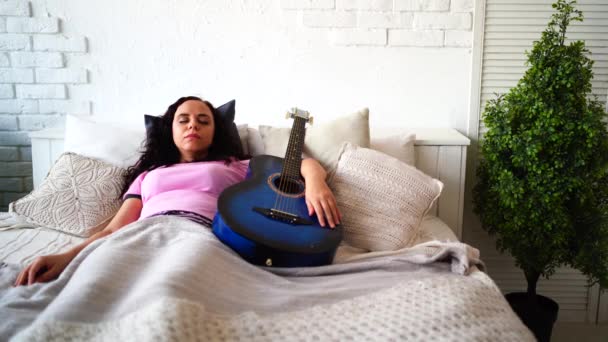 Mujer Joven Descansando Abrazo Con Guitarra Habitación Mujer Adulta Pijama — Vídeo de stock