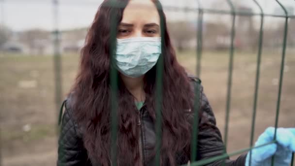 Close Dari Wanita Muda Bertopeng Medis Wajahnya Melalui Pagar Wanita — Stok Video