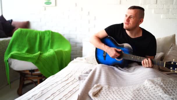 Göğsünde Dövme Olan Genç Bir Adam Yatak Odasında Gitar Çalar — Stok video