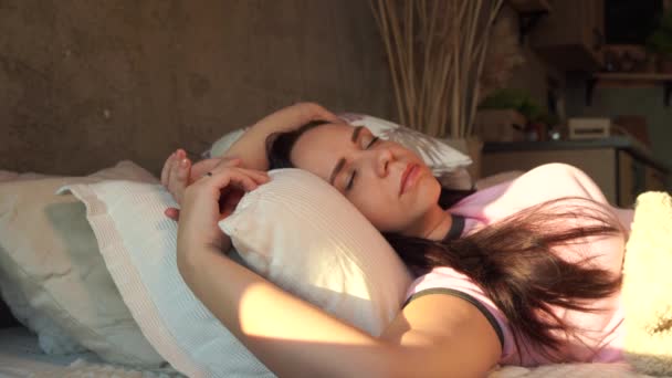 早上穿着睡衣的年轻女人躺在床上 漂亮的成年女性打呵欠 躺在一堆枕头上 — 图库视频影像