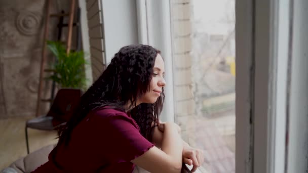 Eine Schöne Frau Schaut Aus Dem Fenster Und Über Etwas — Stockvideo