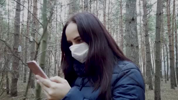 얼굴에 의료용 마스크를 휴대폰으로 전염병에 뉴스를 있습니다 여성은 질병으로부터 자신을 — 비디오