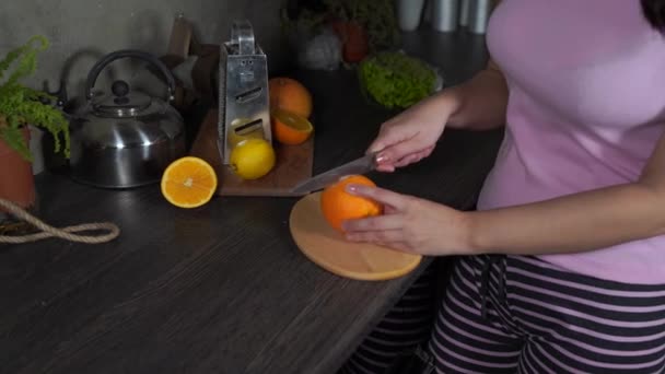 女人在厨房的木板上切水果 女人的手是用刀割橙色的 — 图库视频影像