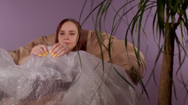 Young Woman Plays Bubble Wrap Sitting Armchair Room Brunette Calms — Stock Video