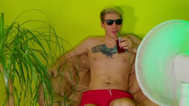 Young Man Bare Torso Drinks Cocktail Straw Sitting Armchair Fan — Stock Video