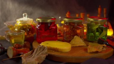 Siyah arka planda üç kavanoz taze reçel yakın ışık ve buharla. Ön planda taze reçel, arka planda oyun ve çay.