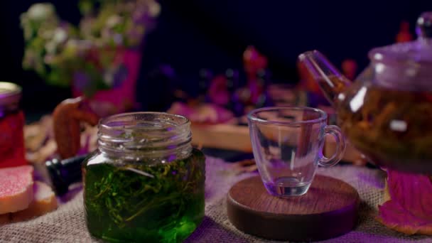 将小罐子与果酱和空杯子一起放在桌子上 难以辨认的女人把绿茶倒入杯子里 茶道的概念 — 图库视频影像
