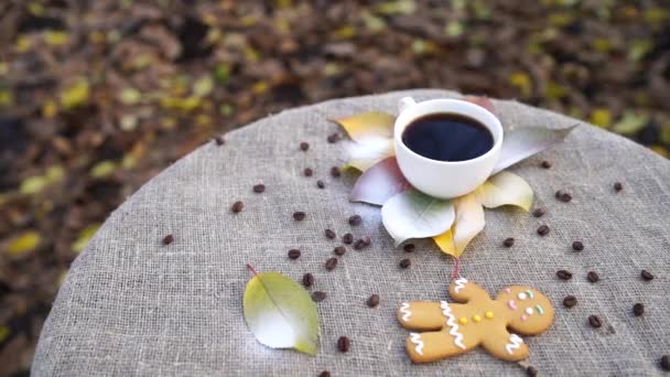 看到甜姜饼人和一杯浓郁的浓缩咖啡放在亚麻布上的五彩缤纷的秋叶上 — 图库视频影像