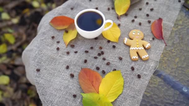 Top kilátás édes mézeskalács ember és csésze erős eszpresszó kávé közelében elhelyezett színes őszi levelek az asztalon vászon ruha a parkban