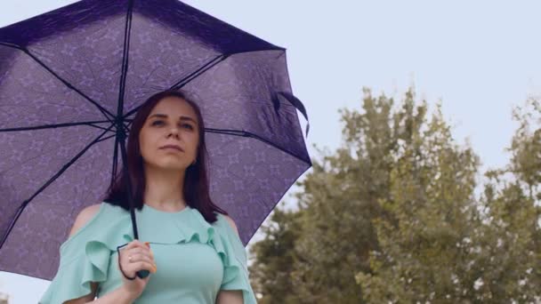 Tankeväckande kvinna med paraply i molnigt och blåsigt väder. Söt kvinna tittar bort, väntar på regn på gatan på sommaren. — Stockvideo