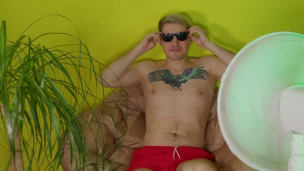 Young Man Bare Torso Puts Sunglasses Sitting Armchair Fan Adult — Stock Video