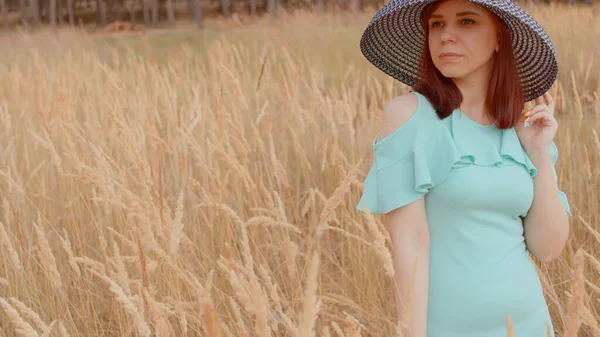 若い女性のドレスや帽子の小麦畑に立っている 可愛い女性のポーズ小麦の耳の中に立って — ストック写真