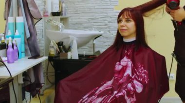 Saç kurutma makinesi kullanan bir kuaförün yakın çekimi saç kesiminden sonra müşterinin kafasını kurutur. Bir kuaför kuaförde bir kadın için saç stili yapar.