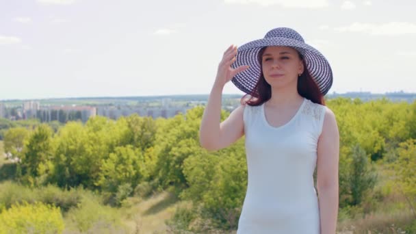 Jonge Vrouw Witte Jurk Elegante Hoed Zonnige Dag Heuvelachtig Terrein — Stockvideo