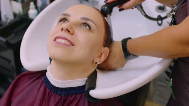 年轻女子与理发师洗头发廊 在染发后 女发型师冲洗客户的头发 — 图库视频影像