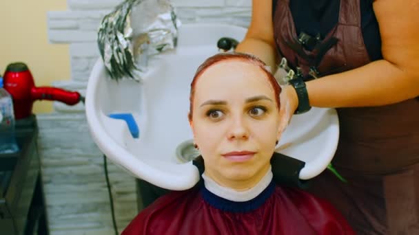 年轻的女人坐在那里 在美容院的理发过程中把头靠在地板上 不认识的人在美容院上色后 洗掉客户的头发 护理与美的概念 — 图库视频影像
