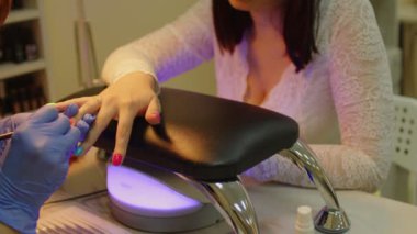 Manikür ustası güzellik salonunda profesyonel manikür yaptırıyor, kadın oje sürüyor. Güzellik salonunda manikür.