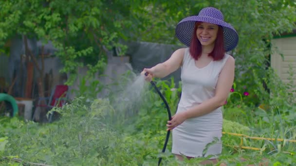 白いドレスとホースからエレガントな帽子散水植物園の若い女性 庭の美しい女性の裁判所 有機製品のコンセプトと環境に配慮したライフスタイル — ストック動画