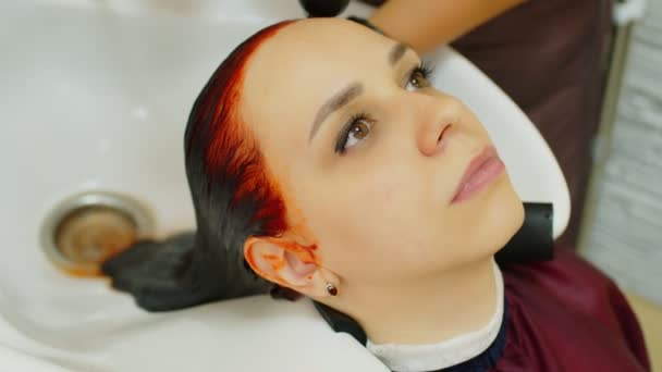 年轻的女人坐在那里 在美容院的理发过程中把头靠在地板上 不认识的人在美容院上色后 洗掉客户的头发 护理与美的概念 — 图库视频影像