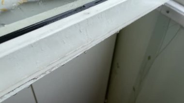 Pencere çerçevesinden zemine damlayan yağmur damlaları balkonda.