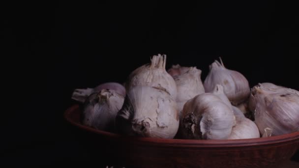 桌上的陶瓷碗里堆满了大蒜 黑色背景的未剥皮蔬菜的收获 — 图库视频影像