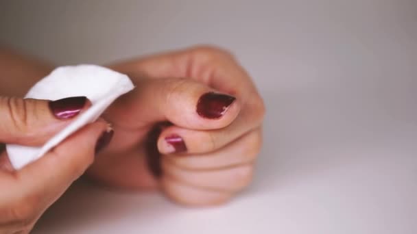 Mujer elimina esmalte de uñas rojo con removedor de esmalte de uñas. La señora quita el esmalte de uñas. Esmalte de uñas rojo con almohadilla de algodón blanco. — Vídeo de stock