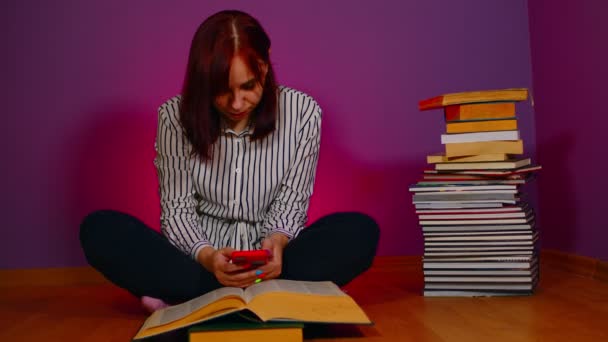 Genç Bir Kadın Kitap Yığınıyla Yerde Oturuyor Mor Arka Planda — Stok video