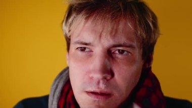 Adamın burnu akmış. Eşarplı genç bir adam sümüğünü siliyor. Soğuk algınlığı olan bir adamın burnu akar. Burundan sümük akıyor.