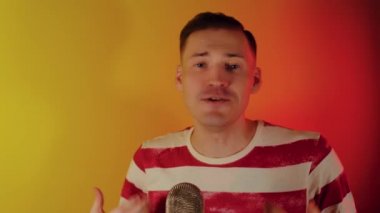 Genç adam mikrofona konuşuyor. Vlog 'u için duygusal blogcu içeriği kaydediyor