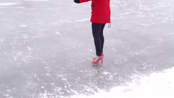 穿着冬衣和高跟鞋的年轻女子在冰上滑行 在冬季室外冰场上的疯女人 — 图库视频影像