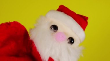 Noel Baba 'nın yumuşak kukla oyuncağı el sallıyor. Sarı arka planda Noel Baba kuklası var. Kukla gösterisi ve yeni yıl tatili kavramı