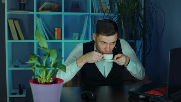 年轻人喝咖啡 坐在电脑前的扶手椅上办公 员工在工作期间在工作场所享用热饮 — 图库视频影像