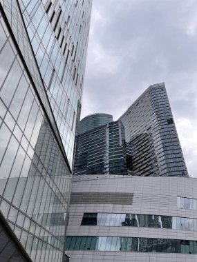 Camdan duvarları olan modern gökdelen cephesi. Şehir merkezindeki bulutlu gökyüzüne karşı cam duvarları olan çağdaş yüksek gökdelenden.