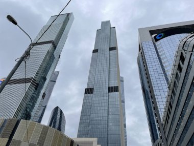 Camdan duvarları olan modern gökdelen cephesi. Şehir merkezindeki bulutlu gökyüzüne karşı cam duvarları olan çağdaş yüksek gökdelenden.