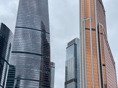 Camdan duvarları olan modern gökdelen cephesi. Şehir merkezindeki bulutlu gökyüzüne karşı cam duvarları olan çağdaş yüksek gökdelenden.