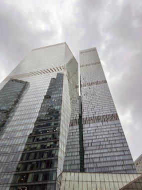 Camdan duvarları olan modern gökdelen cephesi. Şehir merkezindeki bulutlu gökyüzüne karşı cam duvarları olan çağdaş yüksek gökdelenden.