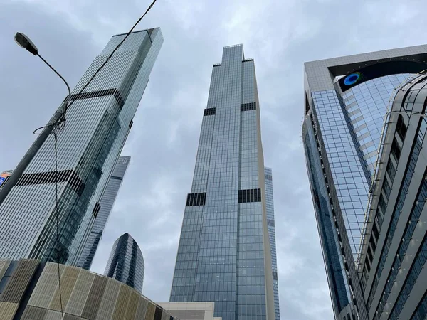 Camdan duvarları olan modern gökdelen cephesi. Şehir merkezindeki bulutlu gökyüzüne karşı cam duvarları olan çağdaş yüksek gökdelenden.