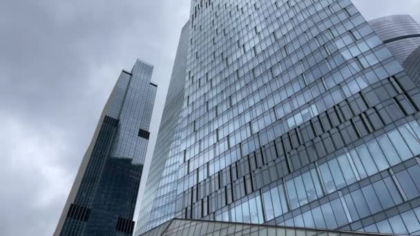 现代玻璃墙摩天大楼的立面在市中心 现代高耸的玻璃墙摩天大楼的下方 与多云的天空相映成趣 — 图库视频影像