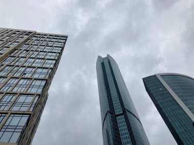 Camdan duvarları olan modern gökdelen cephesi. Şehir merkezindeki bulutlu gökyüzüne karşı cam duvarları olan çağdaş yüksek gökdelenden.