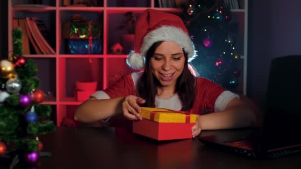 Une jeune femme en costume de Père Noël au bureau ouvre un cadeau contenant de l'argent. Un manager souriant en costume et chapeau du Nouvel An, tenant une pile d'argent — Video