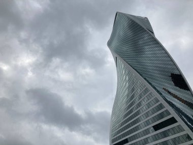 Camdan duvarları olan modern gökdelen cephesi. Şehir merkezindeki bulutlu gökyüzüne karşı cam duvarları olan çağdaş yüksek gökdelenden.