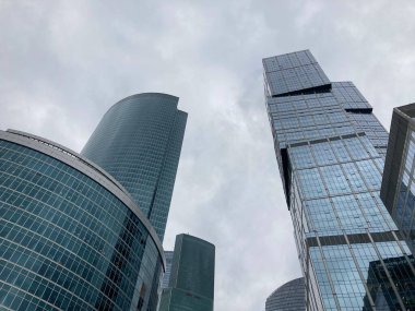 Camdan duvarları olan modern gökdelen cephesi. Şehir merkezindeki bulutlu gökyüzüne karşı cam duvarları olan çağdaş yüksek gökdelenden.