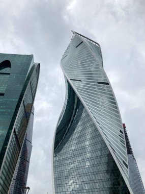 Camdan duvarları olan modern gökdelen cephesi. Şehir merkezindeki bulutlu gökyüzüne karşı cam duvarları olan çağdaş yüksek gökdelenden.