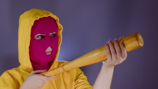 野球バットを手にピンクのバラクラバの若い女性 フーリガン マスクはバットから撃つ — ストック動画