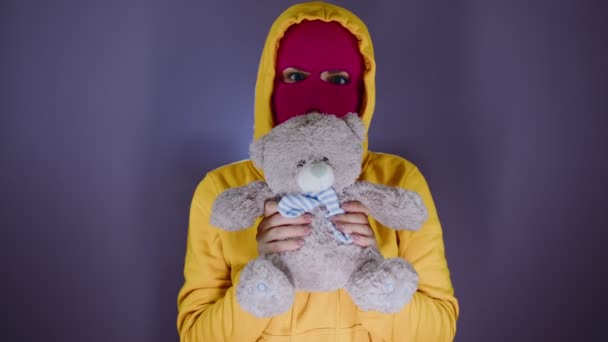 ピンクのバラクラバにテディベアを着た若い女性 手でぬいぐるみのおもちゃとマスク内のフーリガン — ストック動画