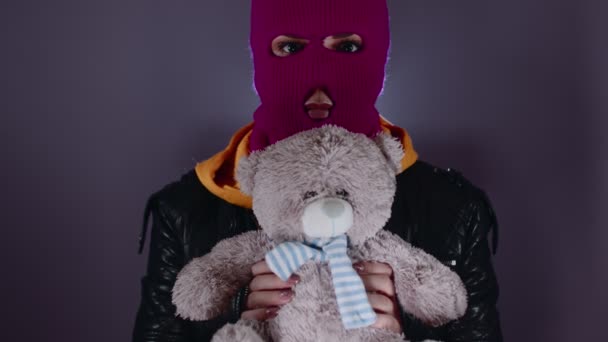 ピンクのバラクラバにテディベアを着た若い女性 手でぬいぐるみのおもちゃとマスク内のフーリガン — ストック動画