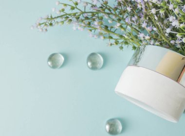 Bitkisel organik doğal dermatoloji kozmetik kremi çiçek desenli cilt bakımı mavi arka planda cam kavanozda